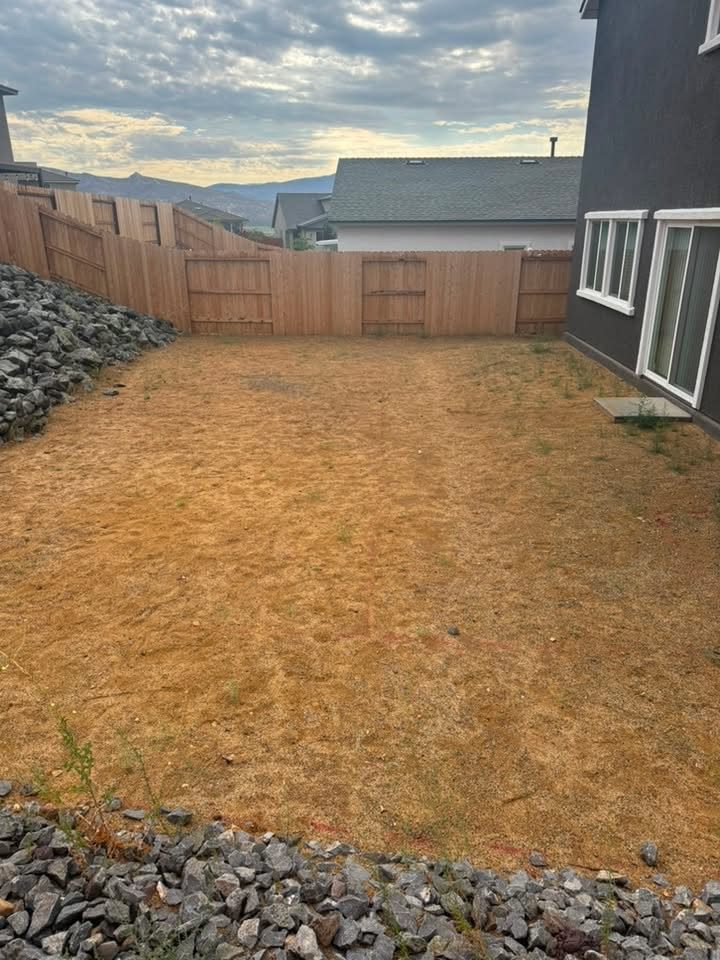Backyard before landscaping, bare dirt with staged rock