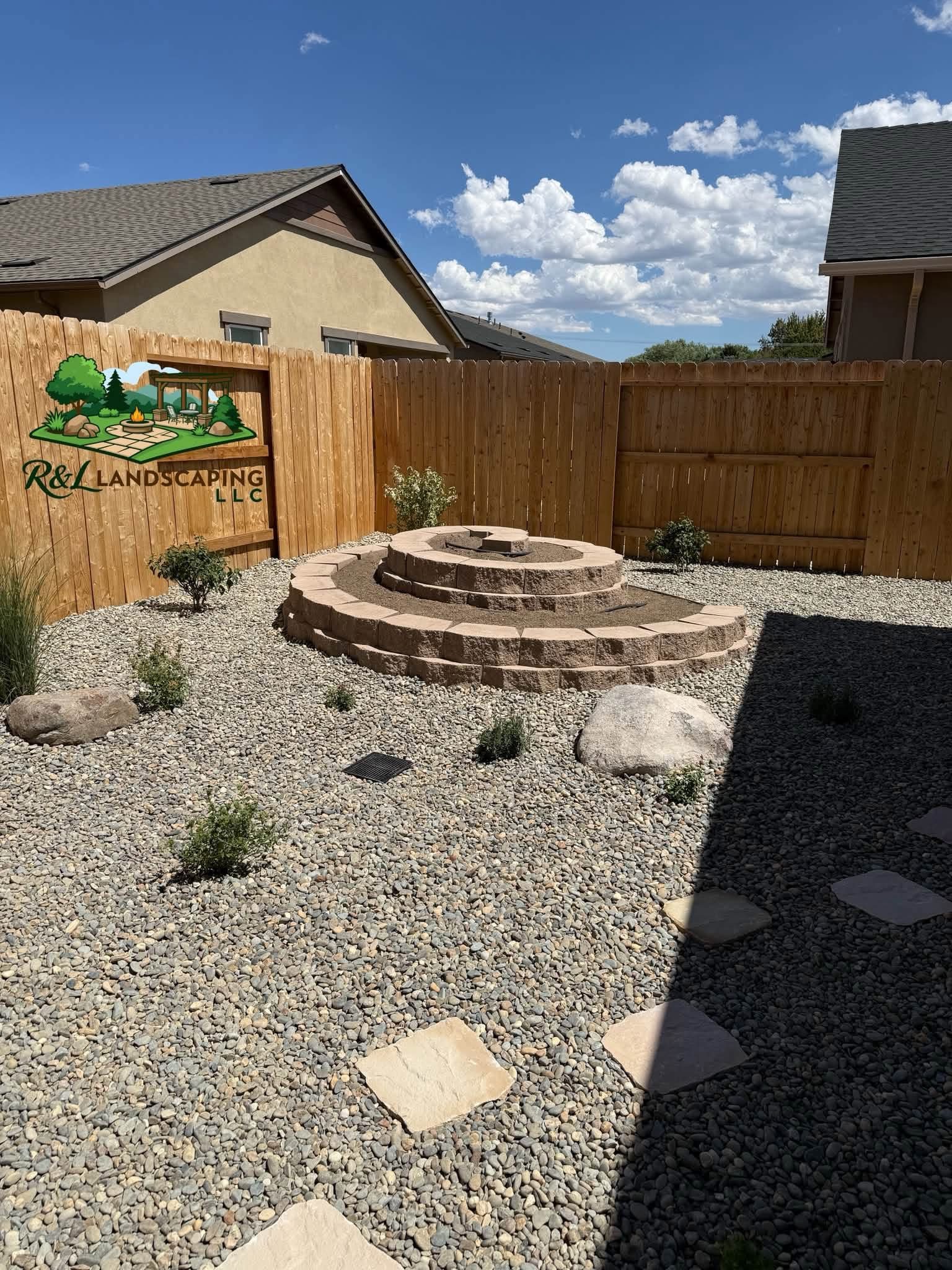 Tiered stone fire pit feature with boulders and new plantings
